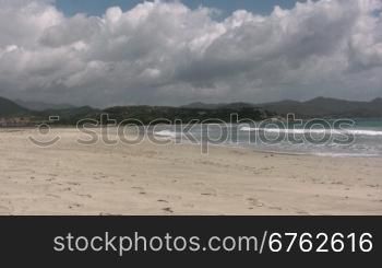 Blick auf einen Strand mit Dnnen im Hintergrund mit Wolken.