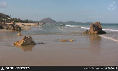 Blick auf einen Strand mit Felsen bei Sonnenschein.