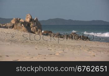 Blick auf einen Strand mit Felsen und Wellen.