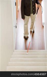 Blind woman using a walking stick on stairway