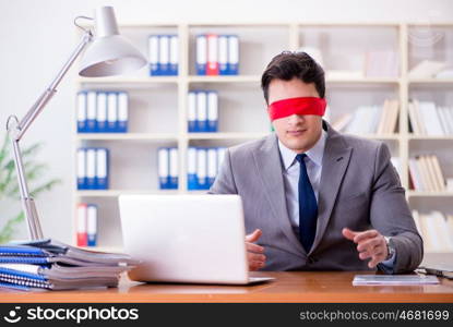 Blindfold businessman sitting at desk in office