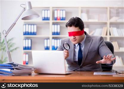 Blindfold businessman sitting at desk in office