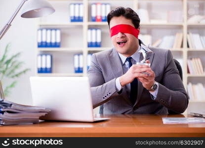 Blindfold businessman sitting at desk in office