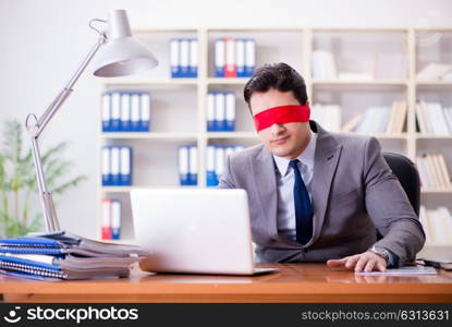 Blindfold businessman sitting at desk in office