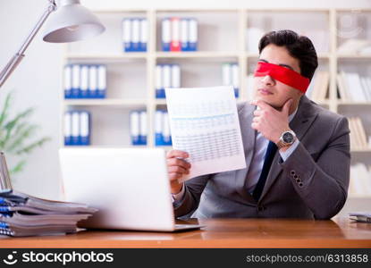 Blindfold businessman sitting at desk in office