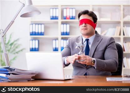 Blindfold businessman sitting at desk in office