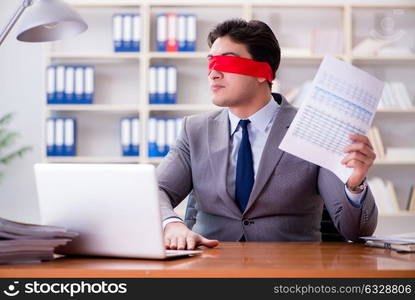 Blindfold businessman sitting at desk in office