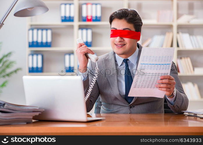 Blindfold businessman sitting at desk in office