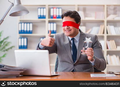 Blindfold businessman sitting at desk in office