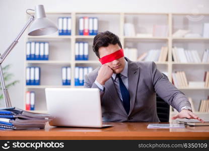 Blindfold businessman sitting at desk in office