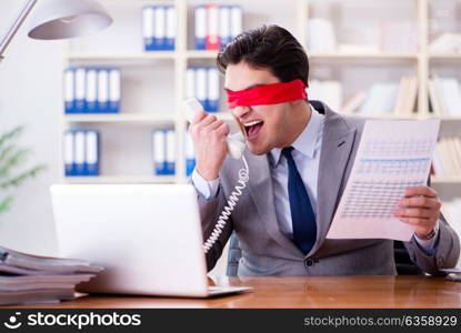 Blindfold businessman sitting at desk in office