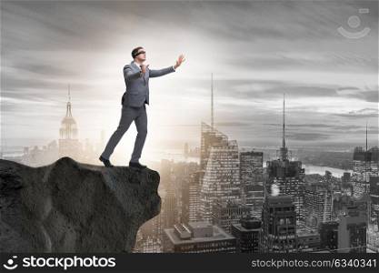 Blindfold businessman standing on tip of cliff