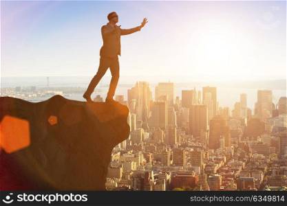 Blindfold businessman standing on tip of cliff