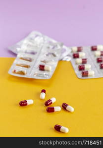 blister packaging of red and white capsules on a yellow background. Blister packaging of red and white capsules on a colored background