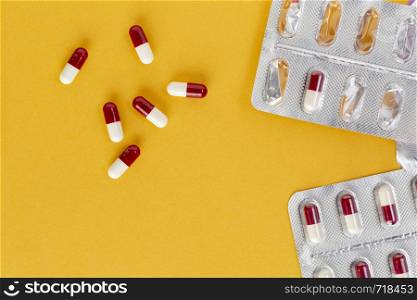 blister packaging of red and white capsules on a yellow background. Open blister pack of red and white capsules on a colored background