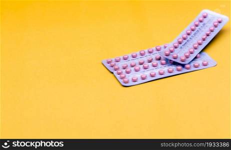 Blister packs of contraceptive pills on yellow background. Hormone pills for treatment hormone acne. Birth control pills. Estrogen and progesterone hormone pills. Pharmacy banner. Prescription drugs.