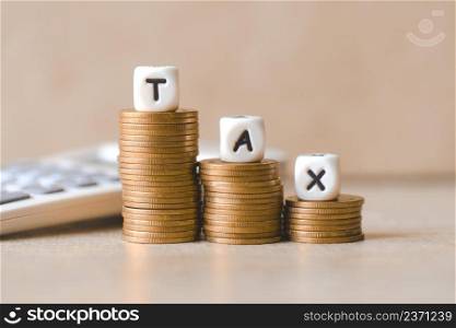 Block word tax on money and calculator on wooden background, TAX on stacked coins financial Tax concept.
