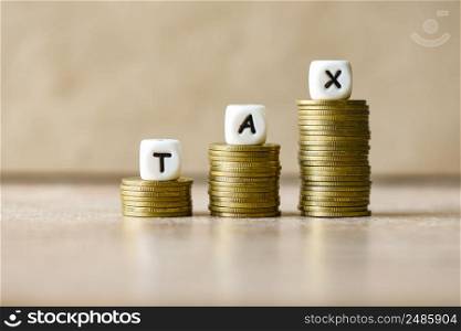 Block word tax on money on wooden background, TAX on stacked coins financial Tax concept.