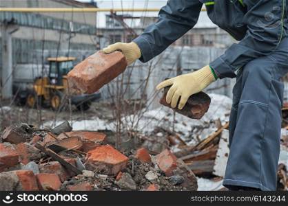 blockages of broken bricks. worker takes down blockages of broken bricks