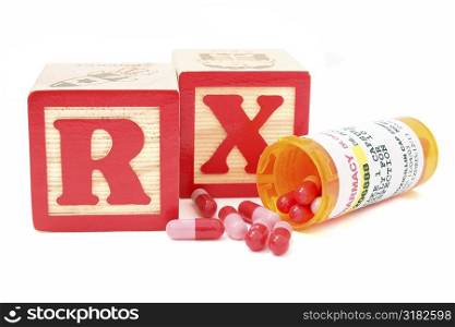 Blocks spell RX (perscription) behind a spilled bottle of generic antibiotics. Store and patient names have been removed. Numbers have been altered in PS.