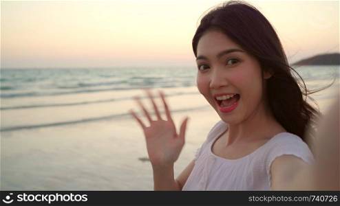 Blogger Asian woman record vlog video on beach, young beautiful female happy using mobile phone make vlog video on beach near sea when sunset in evening. Lifestyle women travel on beach concept.