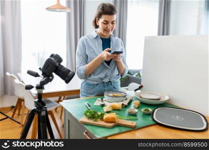 blogging and people concept - happy smiling female photographer or food blogger with camera and smartphone photographing soup in kitchen at home. food blogger with smartphone working in kitchen