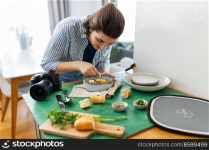 blogging, photographing and people concept - happy smiling female food photographer with camera arranging composition in kitchen at home. food photographer arranging composition in kitchen