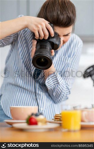 blogging, profession and people concept - female food photographer with camera photographing pancakes, coffee and orange juice in kitchen at home. food photographer with camera working in kitchen