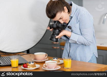 blogging, profession and people concept - female food photographer with camera photographing pancakes, coffee and orange juice in kitchen at home. food photographer with camera working in kitchen