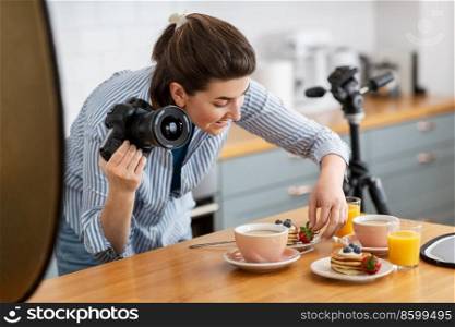 blogging, profession and people concept - happy smiling female food photographer with camera photographing pancakes, coffee and orange juice in kitchen at home. food photographer with camera working in kitchen