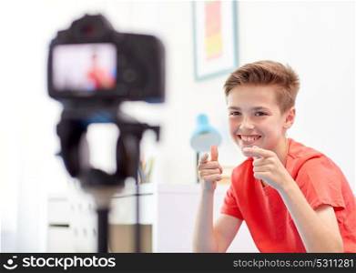 blogging, technology and people concept - happy smiling boy or blogger with camera recording video at home. happy boy with camera recording video at home