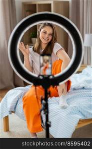 blogging, technology and people concept - happy smiling girl blogger with ring light and smartphone streaming at home. girl blogger with ring light streaming at home