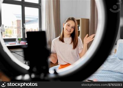 blogging, technology and people concept - happy smiling girl blogger with ring light and smartphone streaming at home. girl blogger with ring light streaming at home