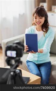 blogging, technology, videoblog and people concept - happy smiling asian woman or blogger with camera recording video blog of book review at home. asian female blogger making video review of book