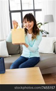 blogging, technology, videoblog and people concept - happy smiling asian woman or blogger with shopping bags recording video blog by camera at home. female blogger making video blog about shopping