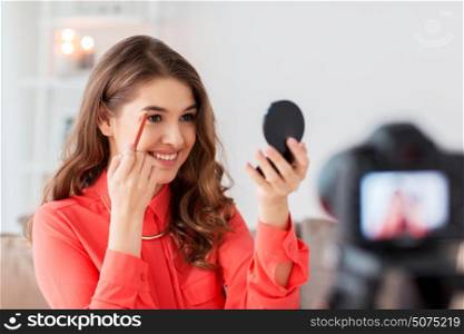 blogging, technology, videoblog, makeup and people concept - happy smiling woman or beauty blogger with eyebrow pencil, mirror and camera recording tutorial video at home. woman with eyebrow pencil recording video at home