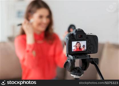 blogging, technology, videoblog, makeup and people concept - happy smiling woman or beauty blogger with bronzer, brush and camera recording tutorial video at home. woman with bronzer and camera recording video