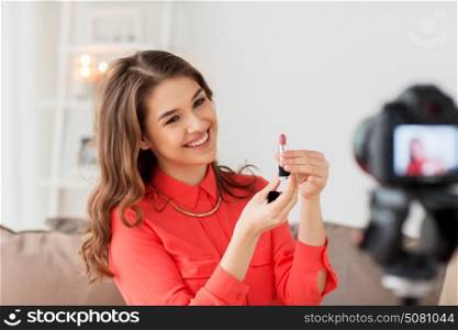 blogging, technology, videoblog, makeup and people concept - happy smiling woman or beauty blogger with lipstick and camera recording tutorial video at home. woman with lipstick and camera recording video