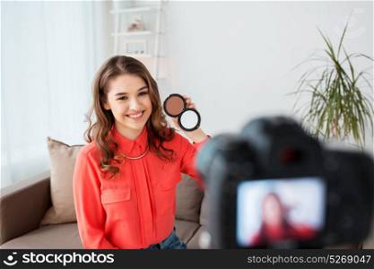 blogging, technology, videoblog, makeup and people concept - happy smiling woman or beauty blogger with bronzer and camera recording tutorial video at home. woman with bronzer and camera recording video