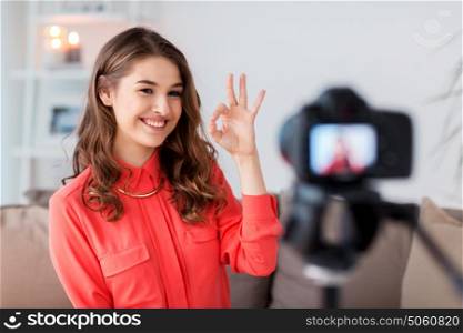 blogging, technology, videoblog, mass media and people concept - happy smiling woman or blogger with camera recording video at home and showing ok hand sign. woman with camera recording video at home