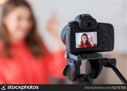 blogging, technology, videoblog, mass media and people concept - happy smiling woman or blogger with camera recording video at home and showing ok hand sign. woman with camera recording video at home