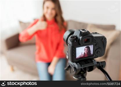 blogging, technology, videoblog, mass media and people concept - happy smiling woman or blogger with camera recording video and showing thumbs up at home. woman with camera recording video at home