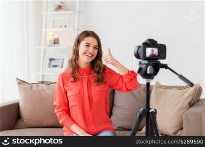 blogging, technology, videoblog, mass media and people concept - happy smiling woman or blogger with camera recording video and showing thumbs up at home. woman with camera recording video at home