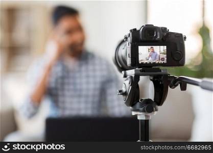 blogging, videoblog and people concept - camera recording video blog of indian male blogger at home. camera recording video blog of indian male blogger