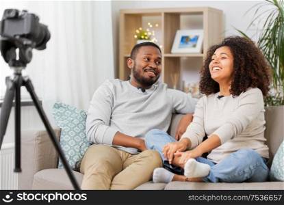 blogging, videoblog and people concept - happy african american couple of video bloggers with camera videoblogging at home. couple of video bloggers with camera at home