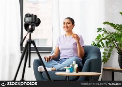 blogging, videoblog and people concept - happy smiling african american female beauty blogger with camera and cosmetics videoblogging at home. female beauty blogger with camera and cosmetics