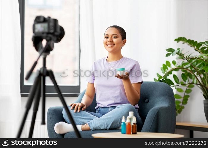 blogging, videoblog and people concept - happy smiling african american female beauty blogger with camera and cosmetics videoblogging at home. female beauty blogger with camera and cosmetics