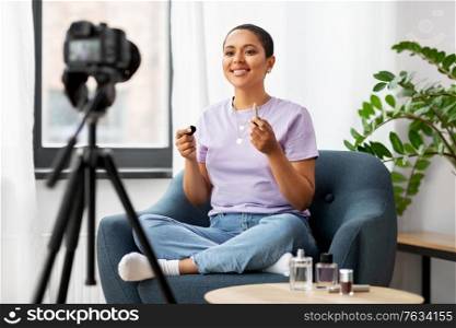 blogging, videoblog and people concept - happy smiling african american female beauty blogger with camera and make up cosmetics videoblogging at home. female beauty blogger with camera and lipstick