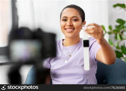blogging, videoblog and people concept - happy smiling african american female video blogger with camera and smart watch videoblogging at home. female blogger with camera video blogging at home
