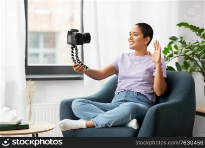 blogging, videoblog and people concept - happy smiling african american female video blogger with camera videoblogging at home. female blogger with camera video blogging at home